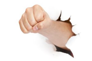 10806512 - fist punching through paper isolated on white background